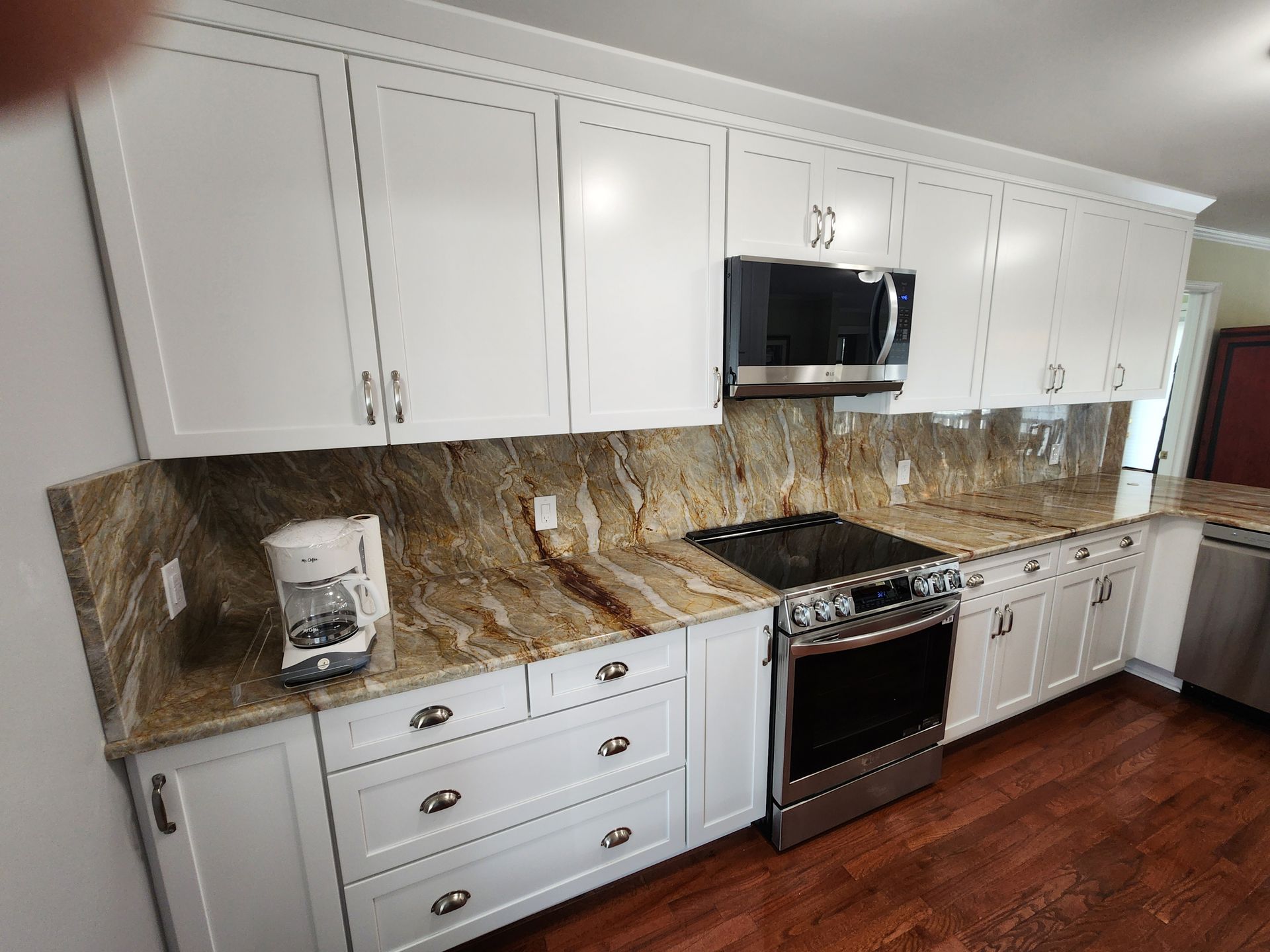 White kitchen cabinets with granite countertop, built-in microwave, and stainless steel range.