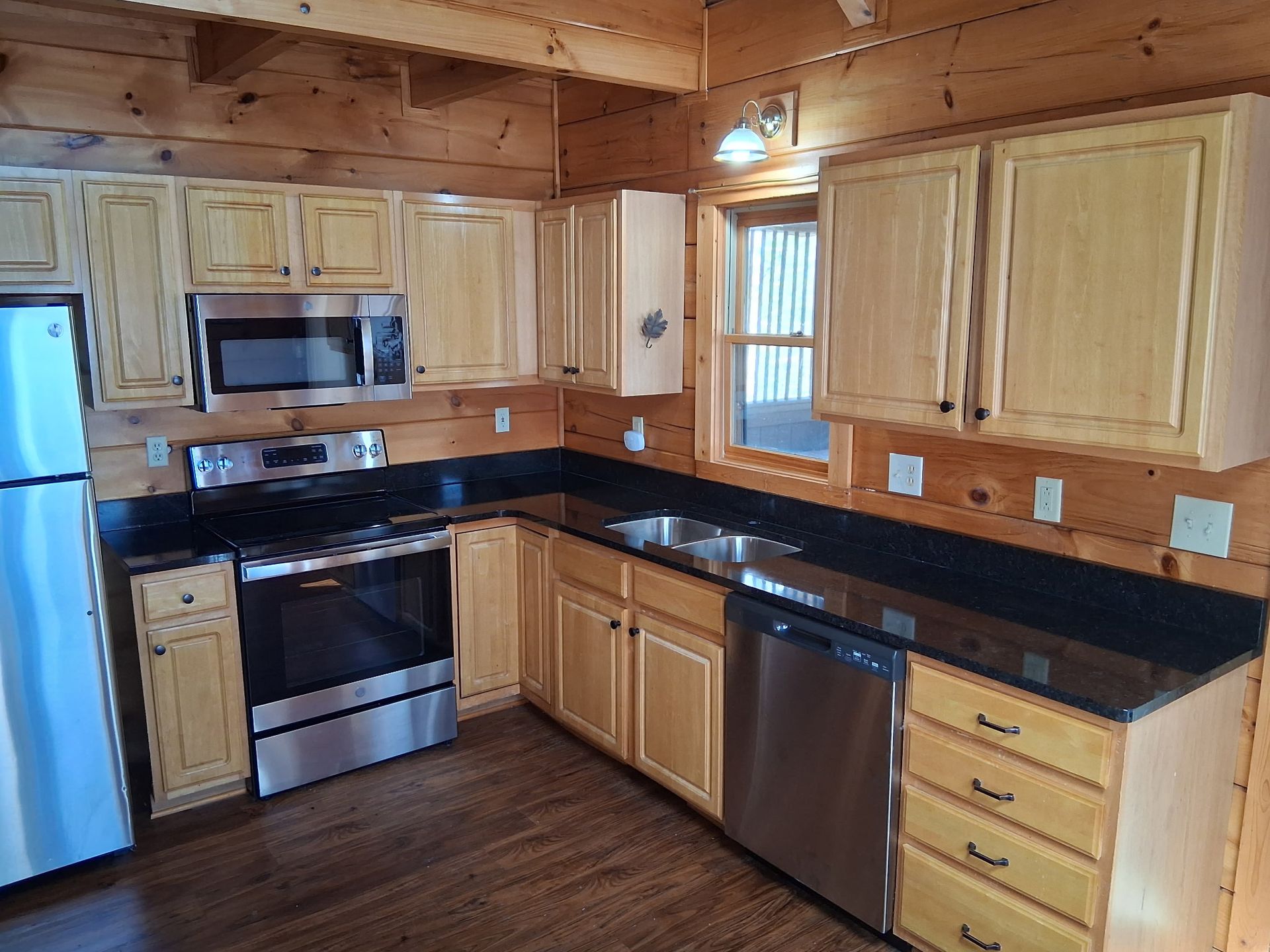 Kitchen with light wood cabinets, stainless steel appliances, and dark countertops.