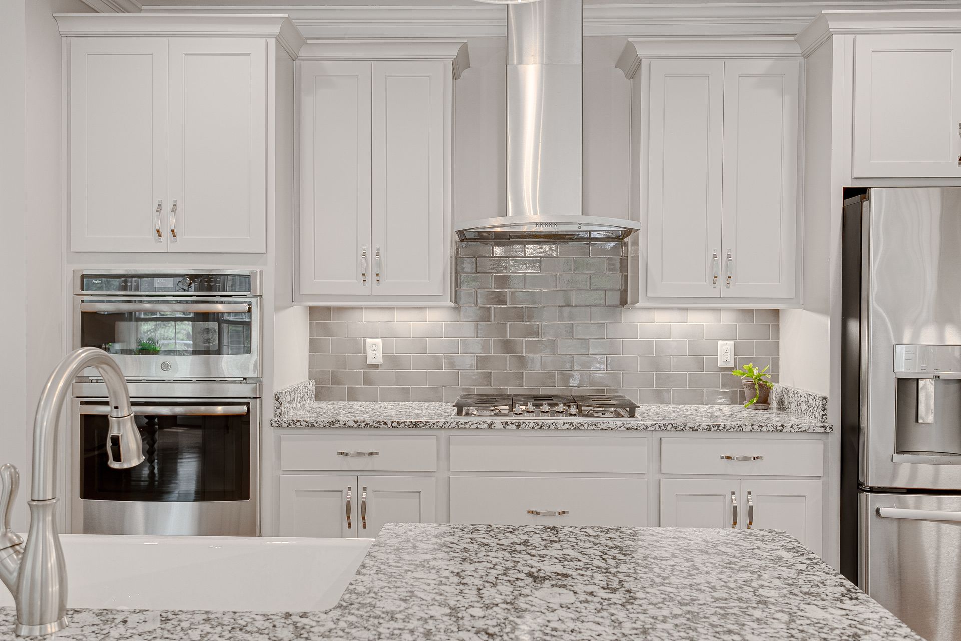 Modern kitchen with white cabinets, granite countertops, stainless appliances, and tile backsplash. Modern kitchen with white cabinets, granite countertops, stainless appliances, and tile backsplash.