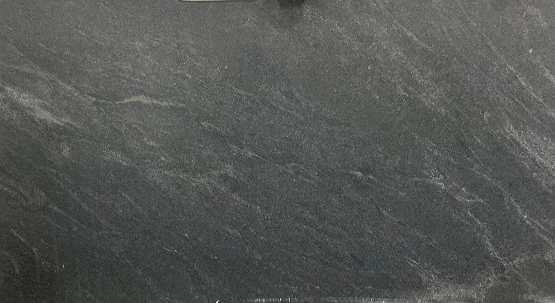 Scratched, dark grey surface with subtle light streaks.