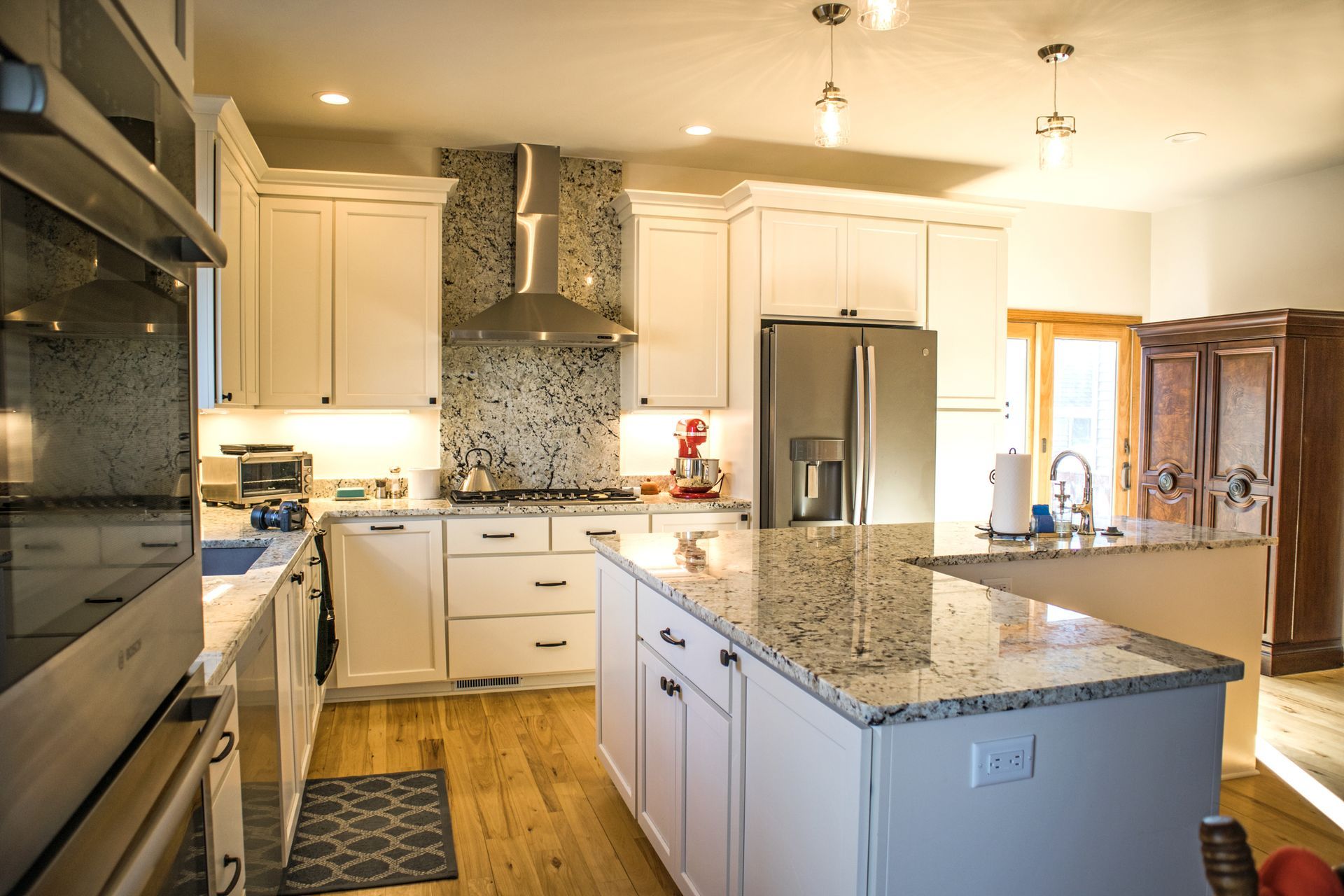 Bright kitchen with white cabinets, island, stainless steel appliances, and granite countertops.