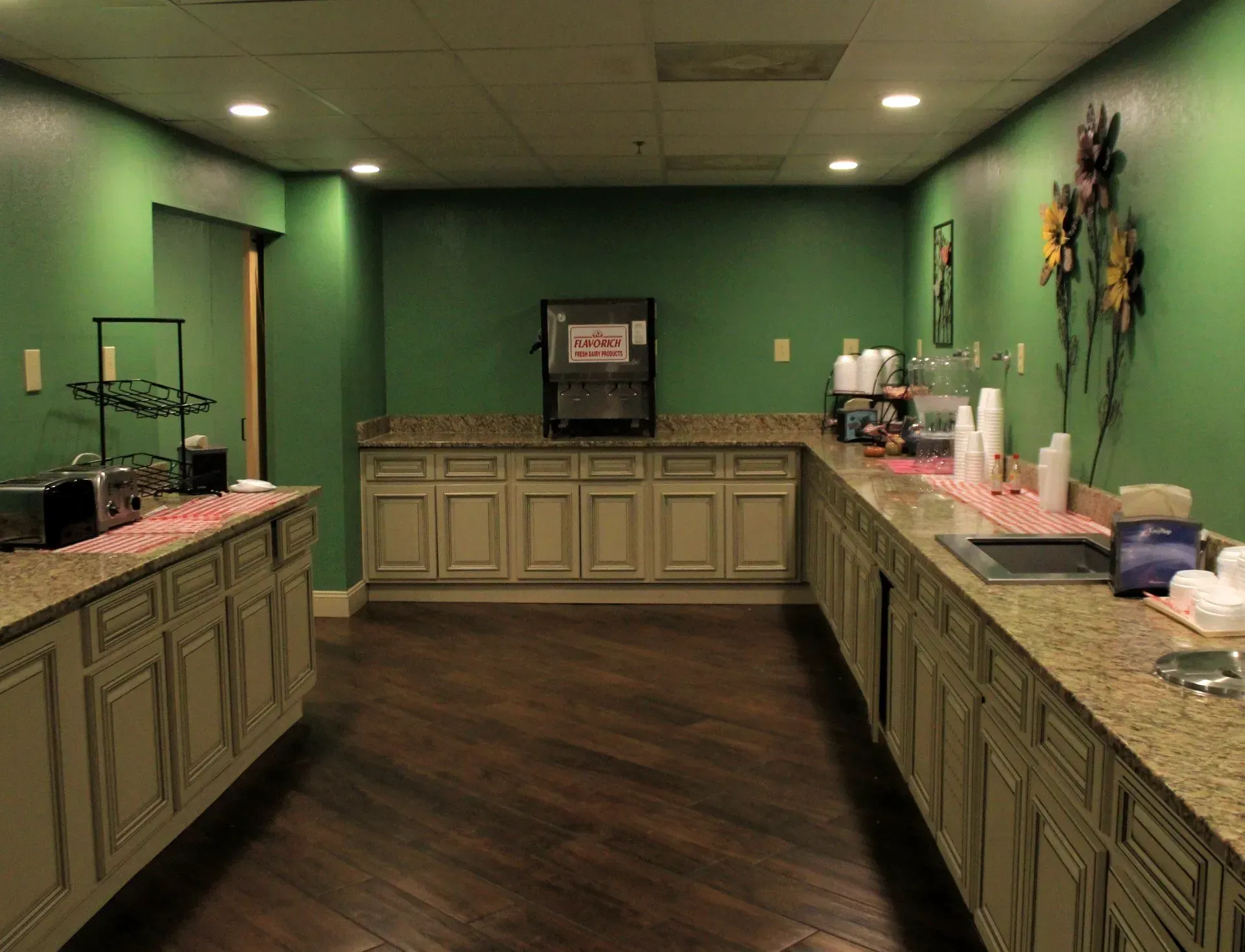 Breakfast bar with green walls, cream cabinets, and dark wood floors.