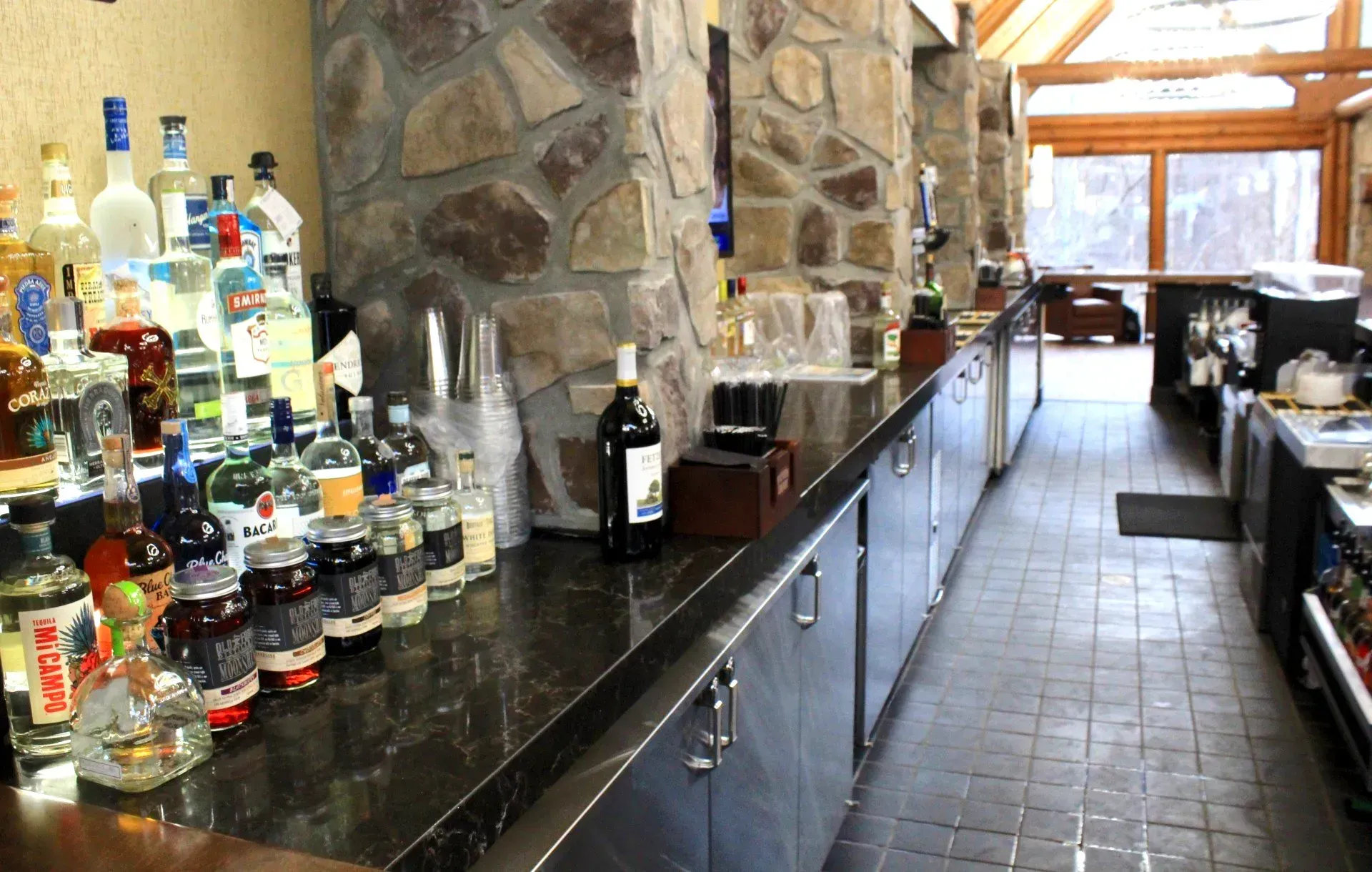 Bar with liquor bottles on counter and stone columns.