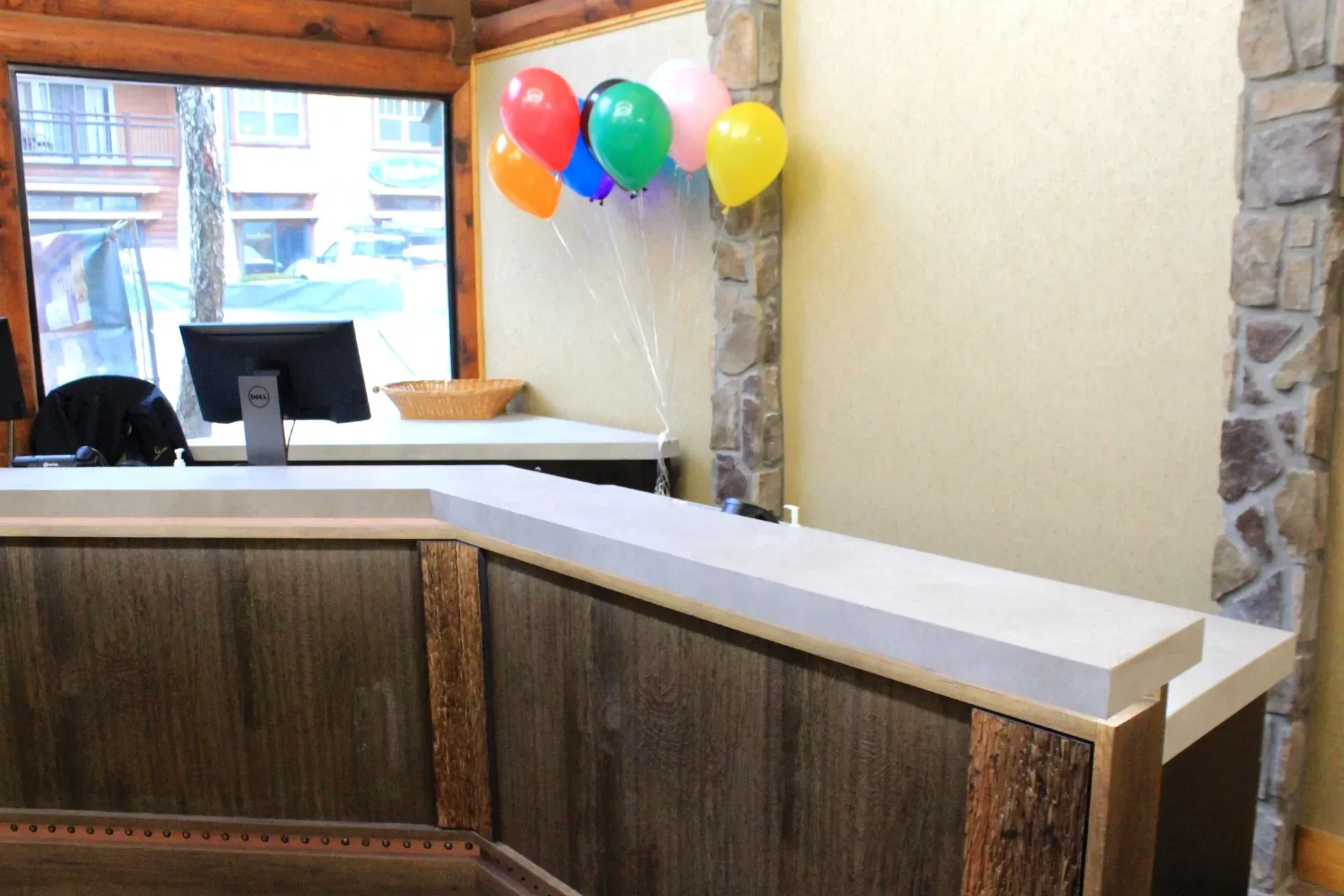 Reception desk with balloons and a window in a rustic setting.