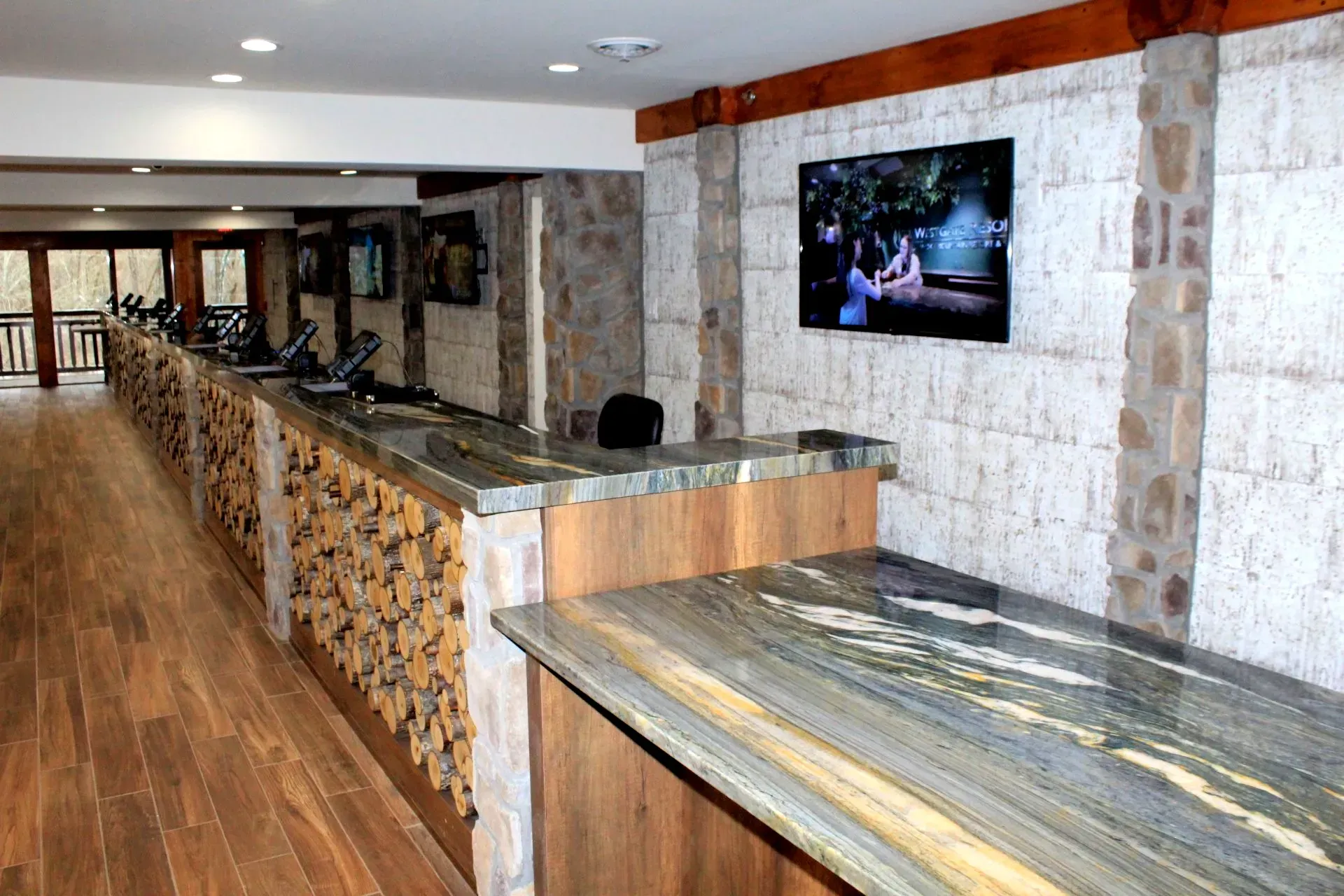 Long counter in room with stone walls, multiple TVs, wooden floors.