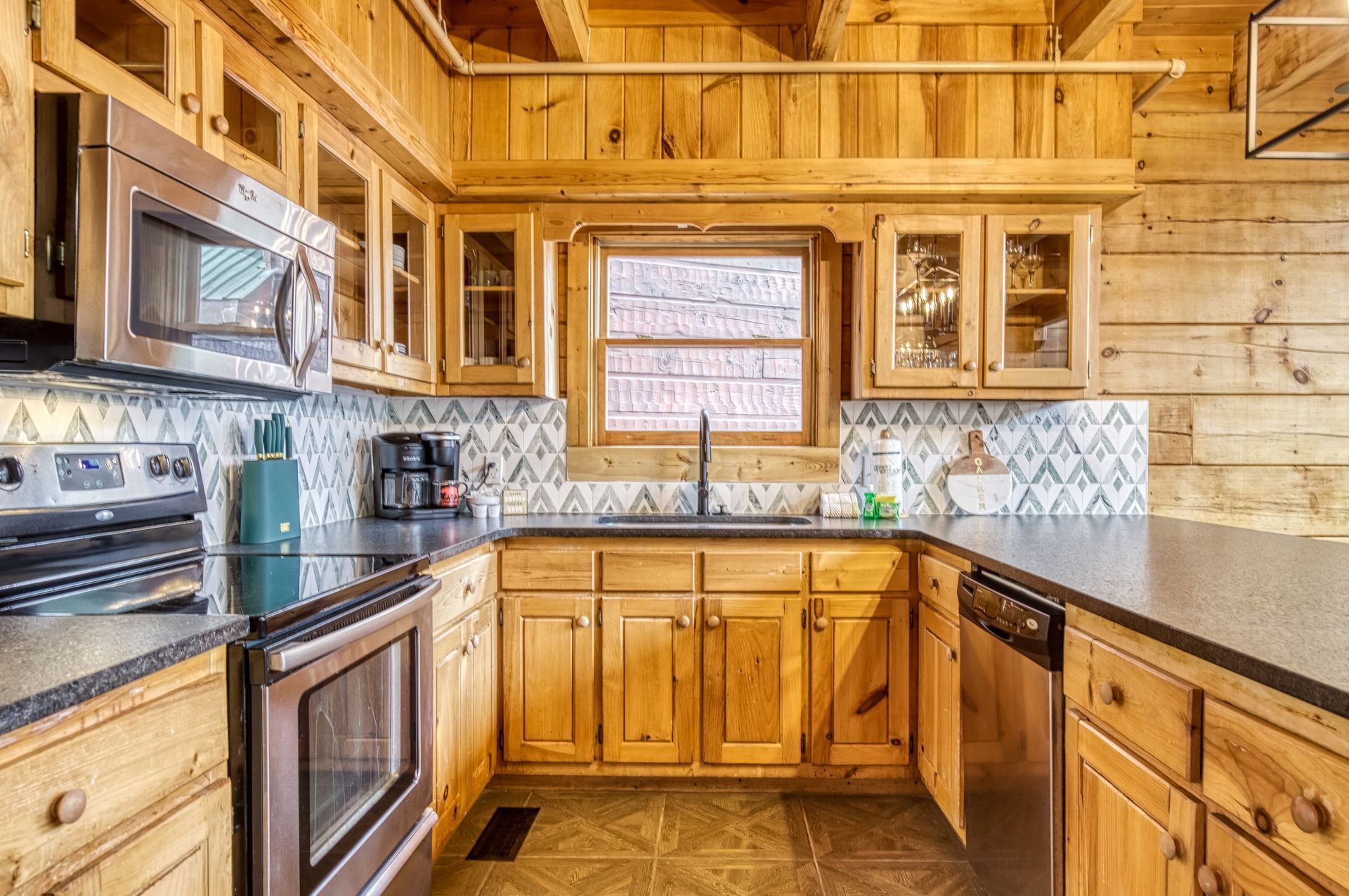 A kitchen with wooden cabinets and walls, stainless steel appliances, and a window above the sink.