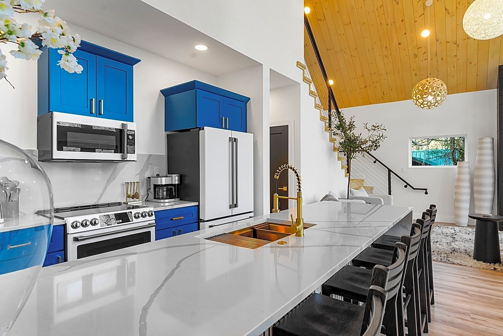 Modern kitchen with blue cabinets, white countertops, and stainless steel appliances.