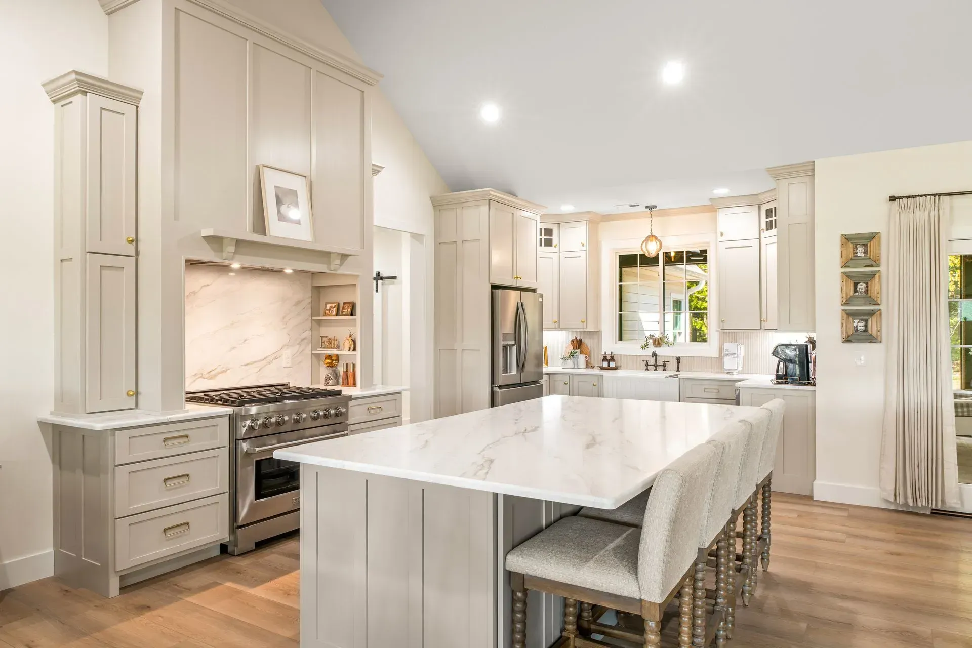 Bright modern kitchen with white cabinets, large island, stainless appliances, and wood floors