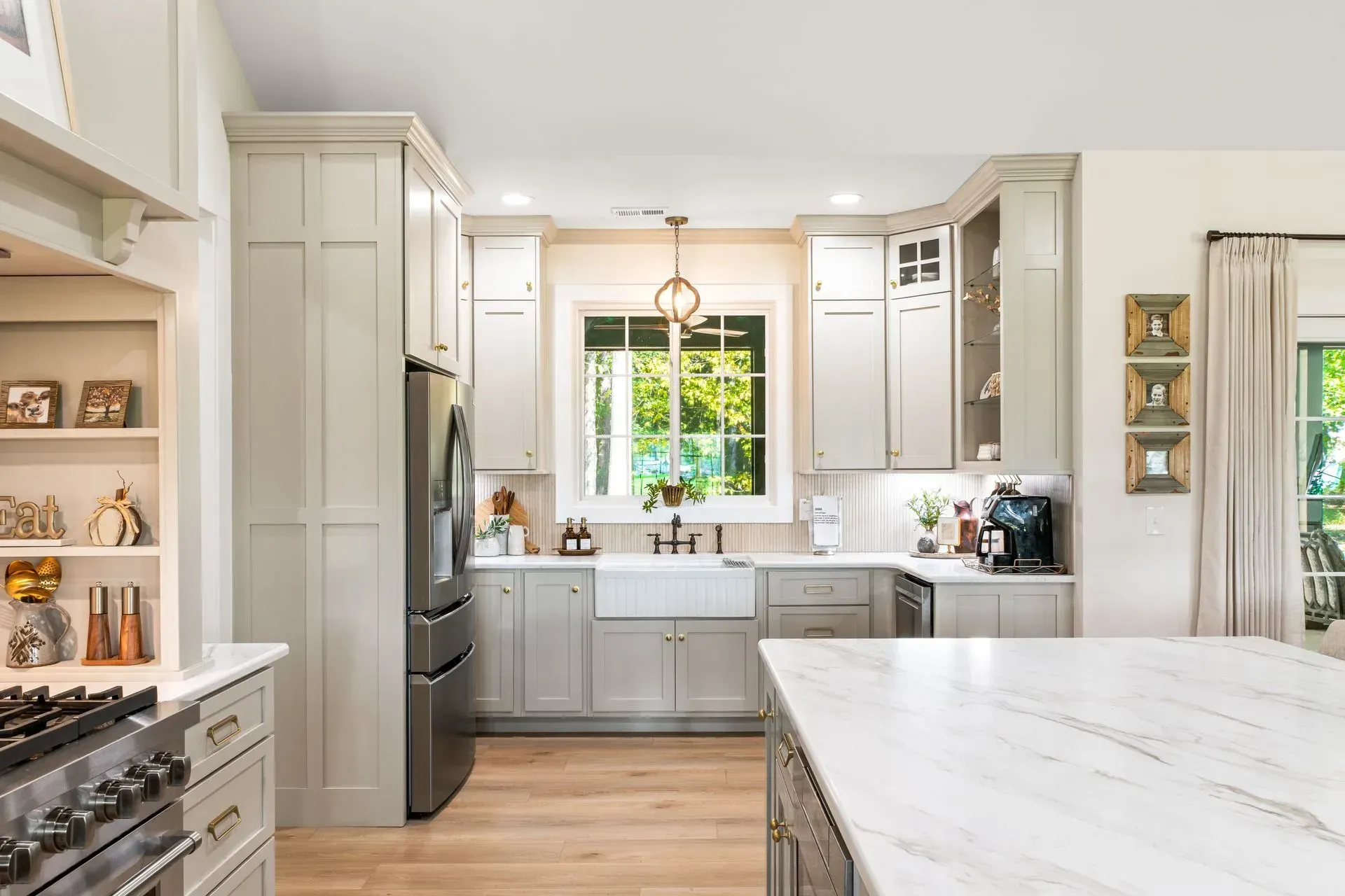 Bright modern kitchen with white cabinets, marble island, and a window over the sink