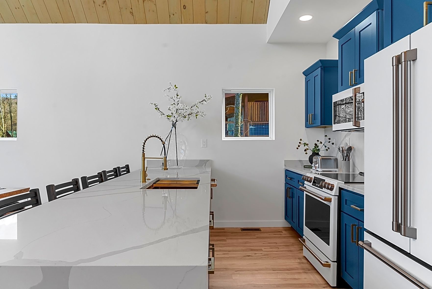 Modern kitchen with blue cabinets, white countertops, and stainless steel appliances.