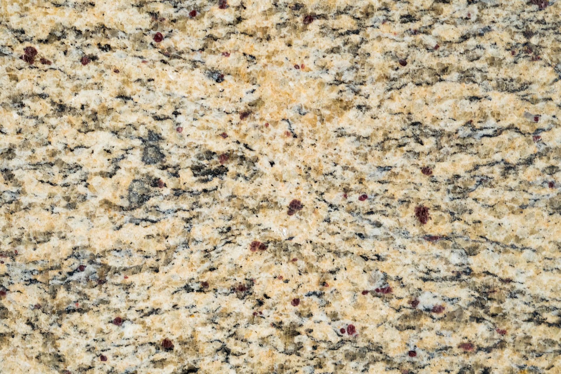 Close-up of a beige granite countertop with black, gray, and red speckles.