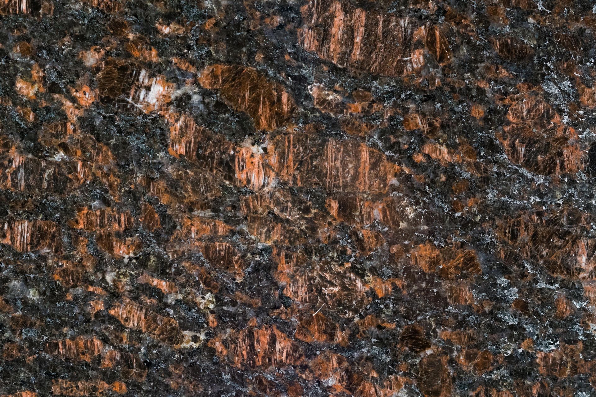 Close-up of polished granite with brown, black, and gray mineral grains.