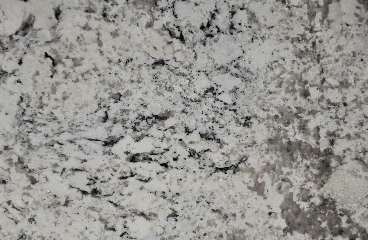 Close-up of a white granite countertop with grey and black veining and speckles.