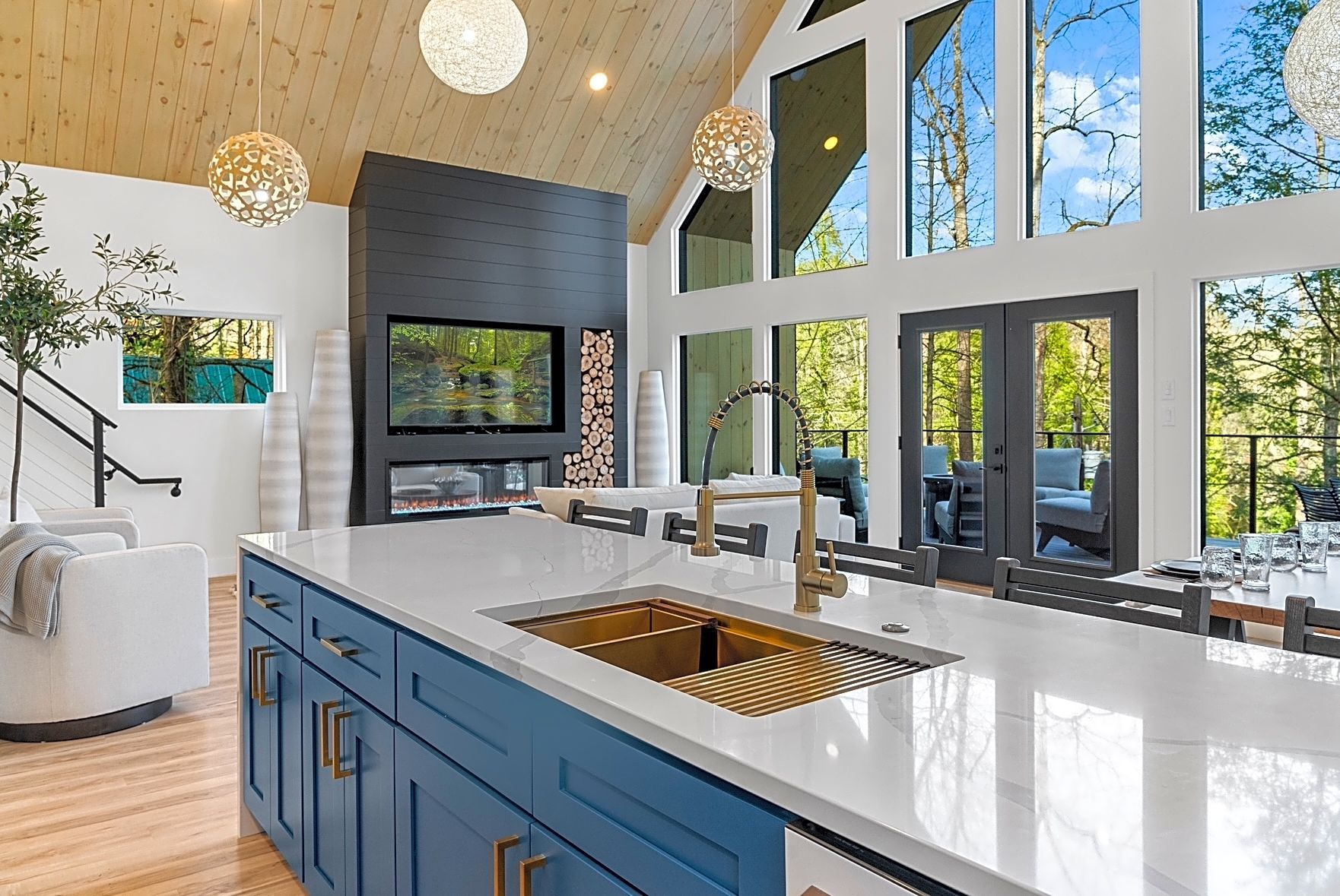 Open kitchen with blue island, gold fixtures, large windows, and a fireplace.
