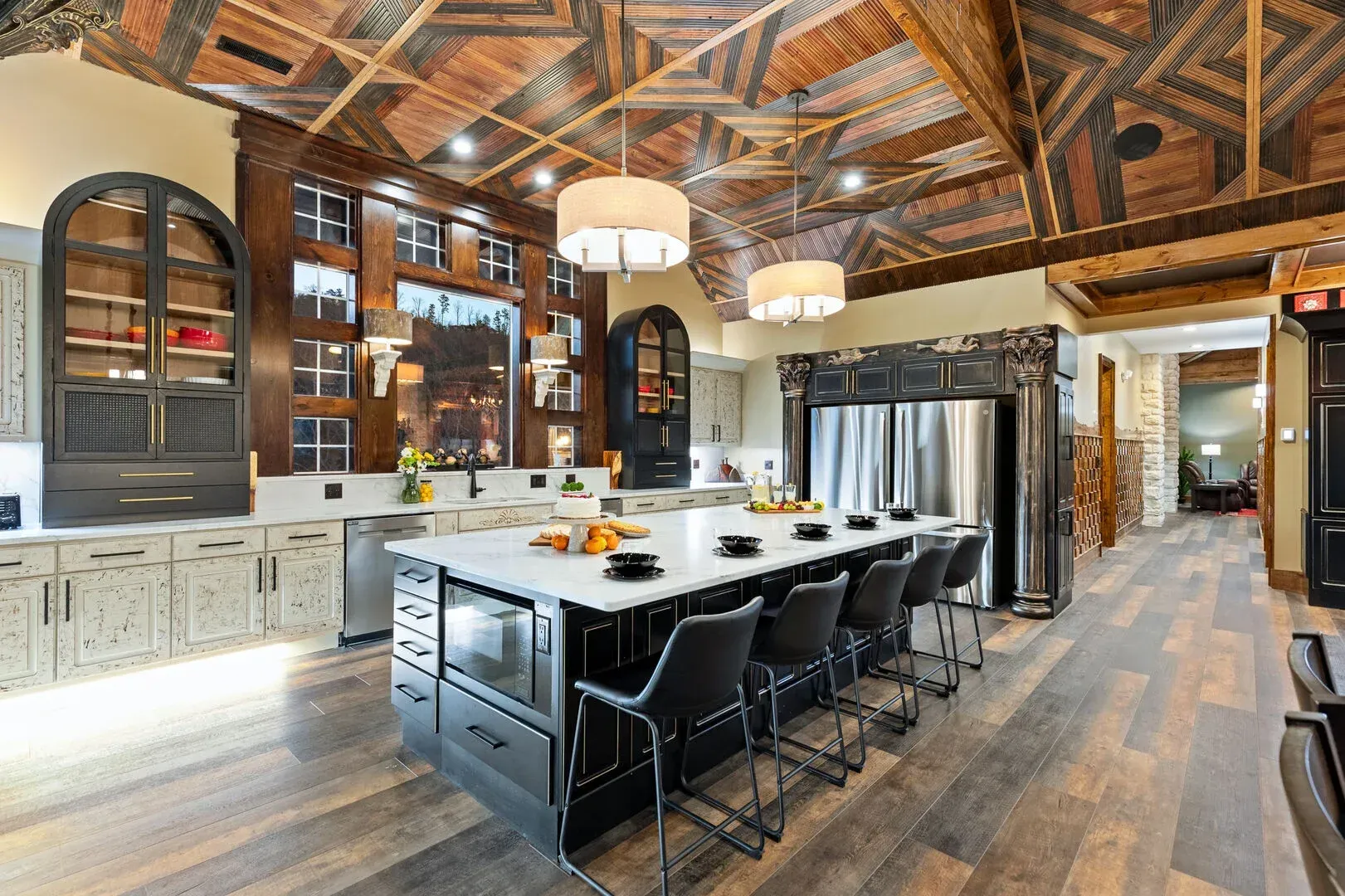 Kitchen with a large island, wood ceiling, and cabinetry. Island has seating, stainless steel appliances.