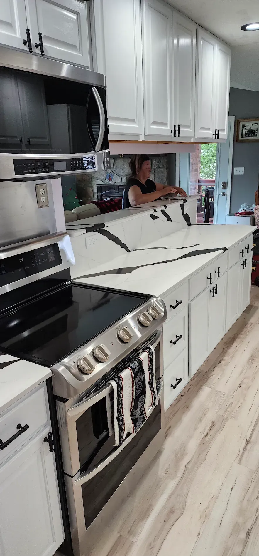 Kitchen with white cabinets, black countertops, and a person in the background.