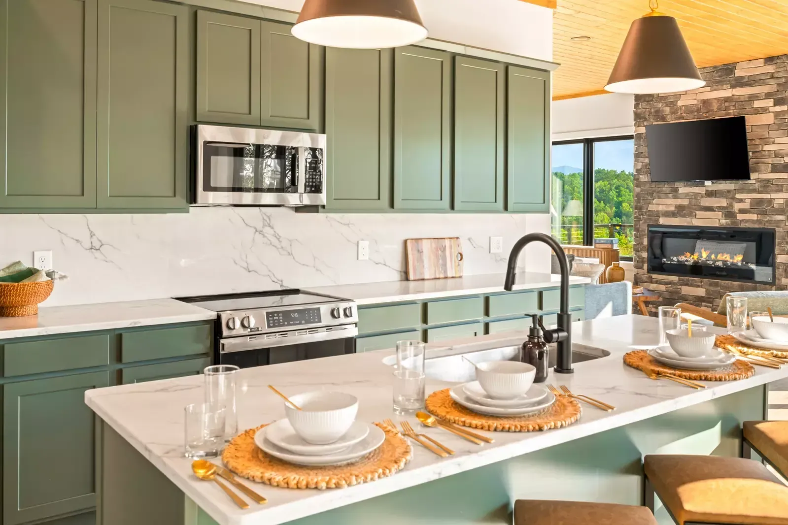 Modern kitchen with sage cabinets, white island, and two place settings on a bright countertop