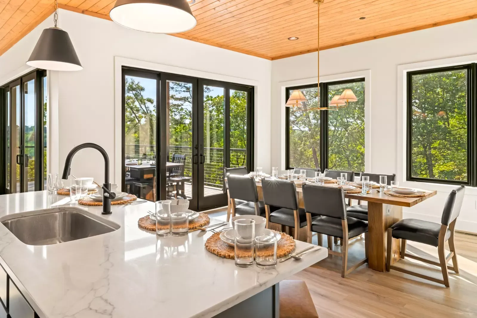 Bright modern dining room with glass doors, large table set for a meal, and a kitchen island in the foreground