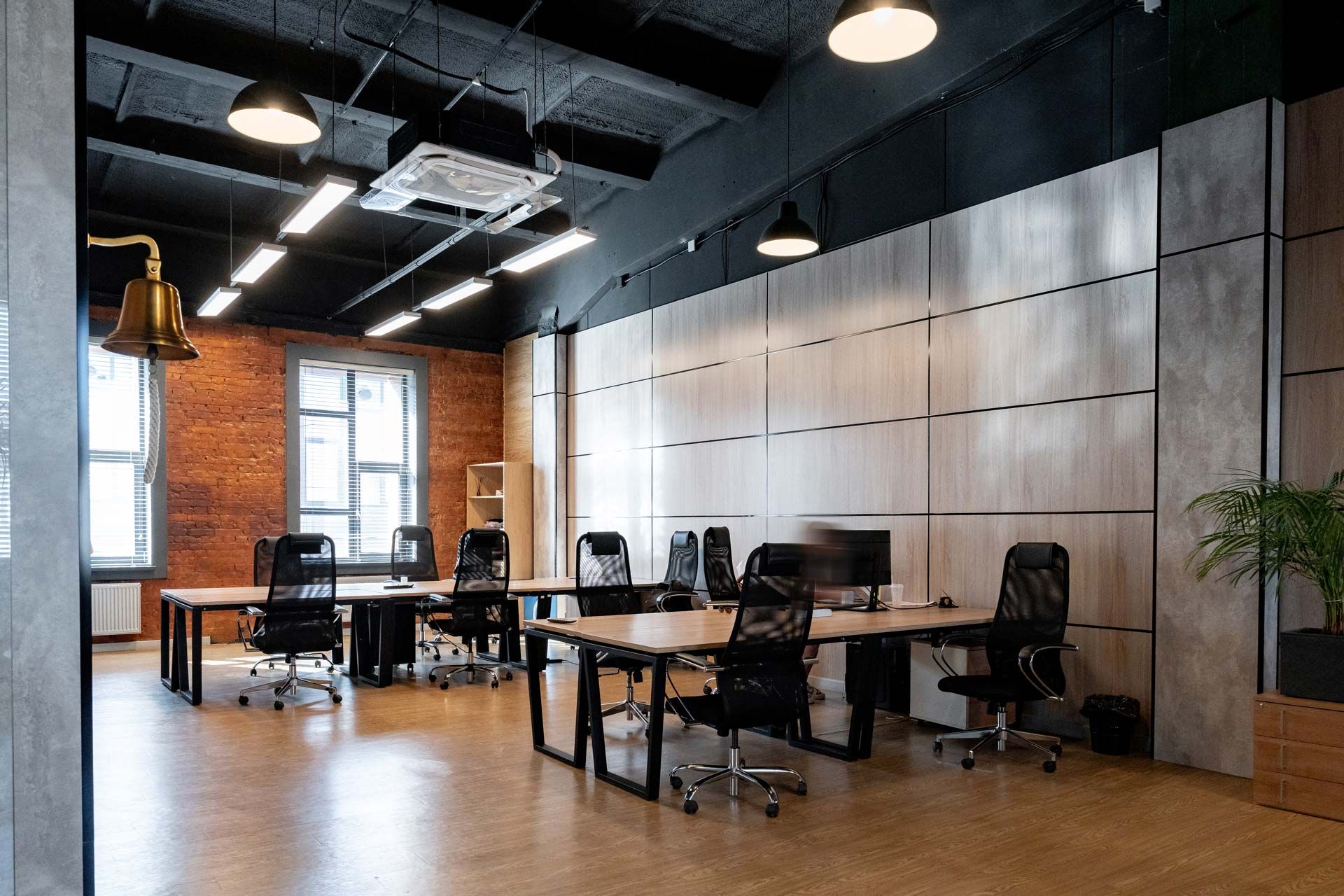 Modern open office with desks, computers, brick wall, and large metal sliding partition doors