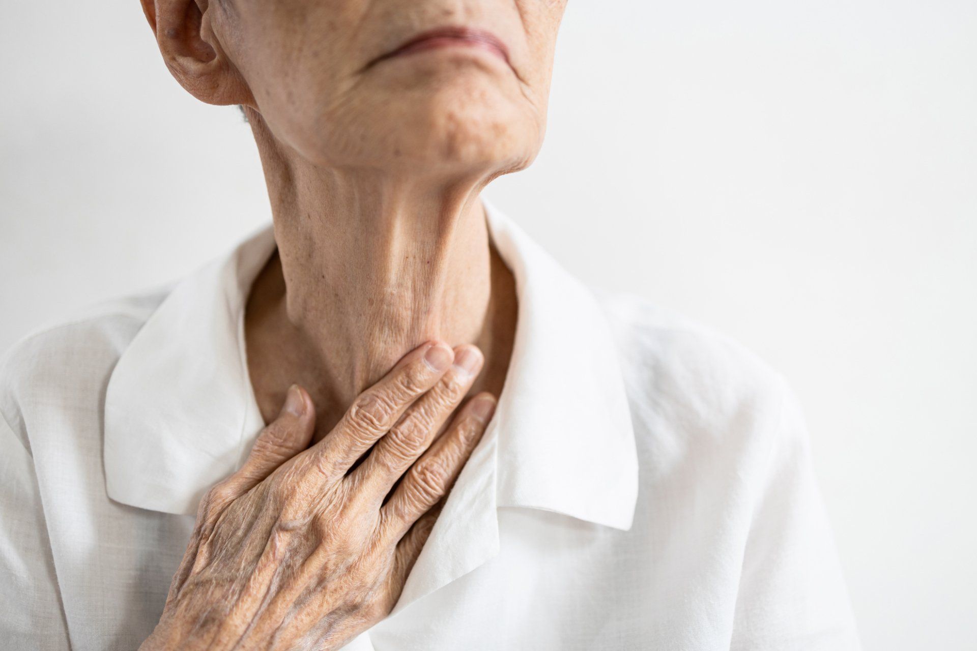 elderly white woman touching neck