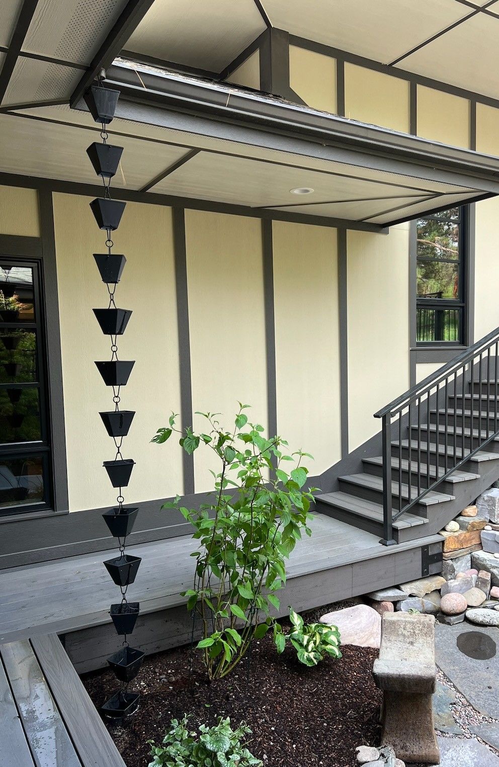 A house with stairs and a rain chain on the porch.