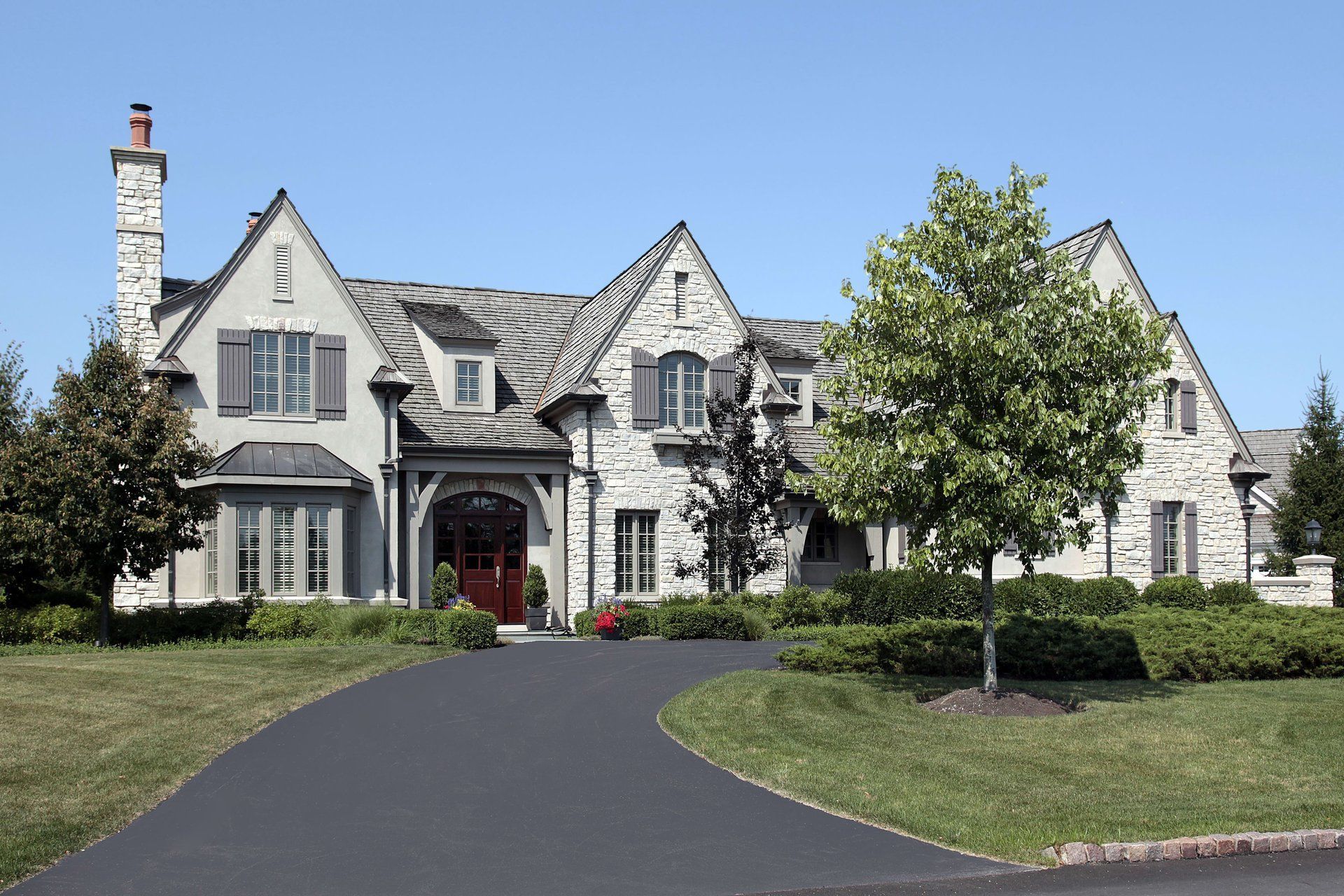 A large white house with a black driveway leading to it