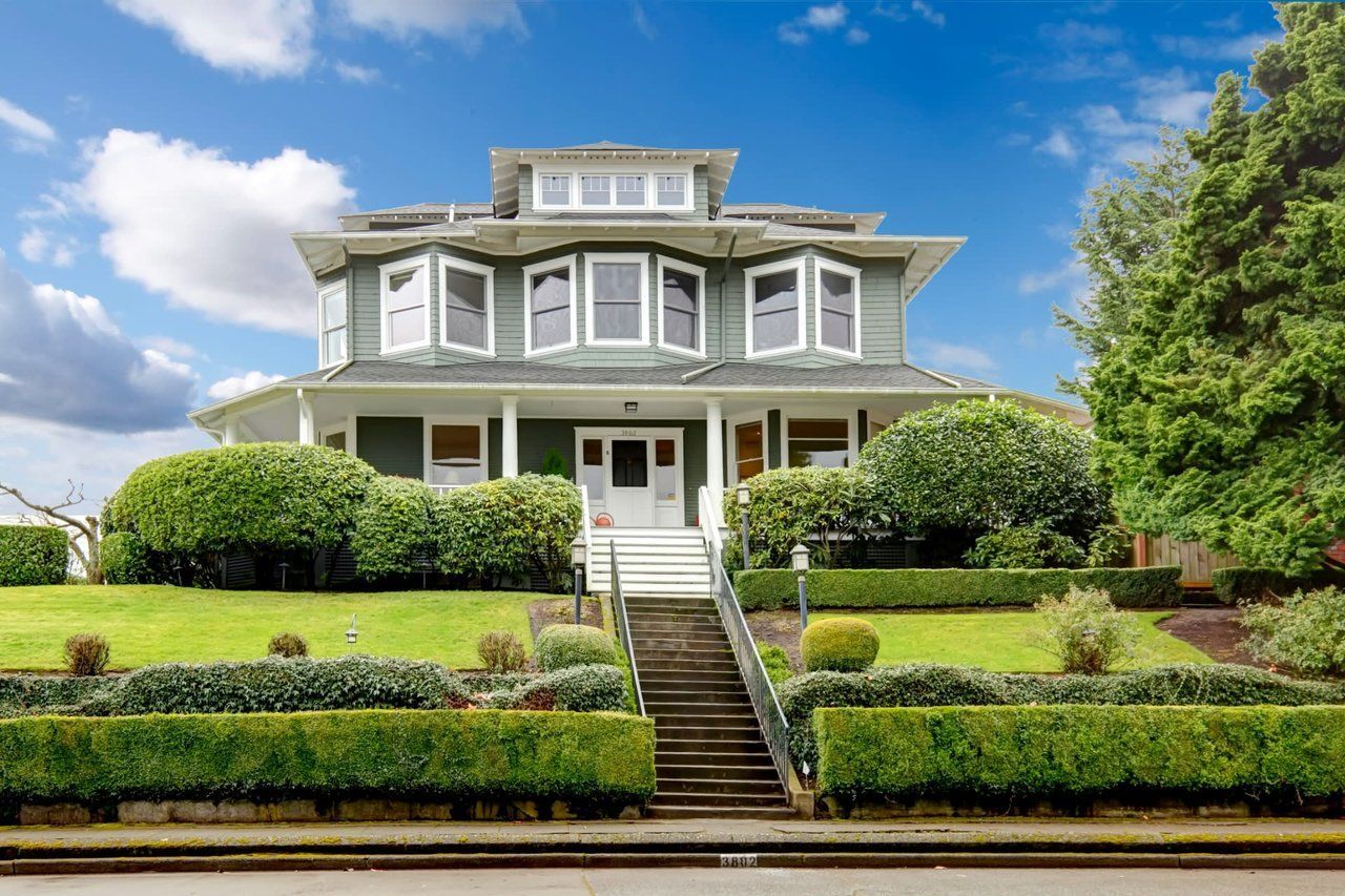 A large house with a lush green lawn and stairs leading up to it.