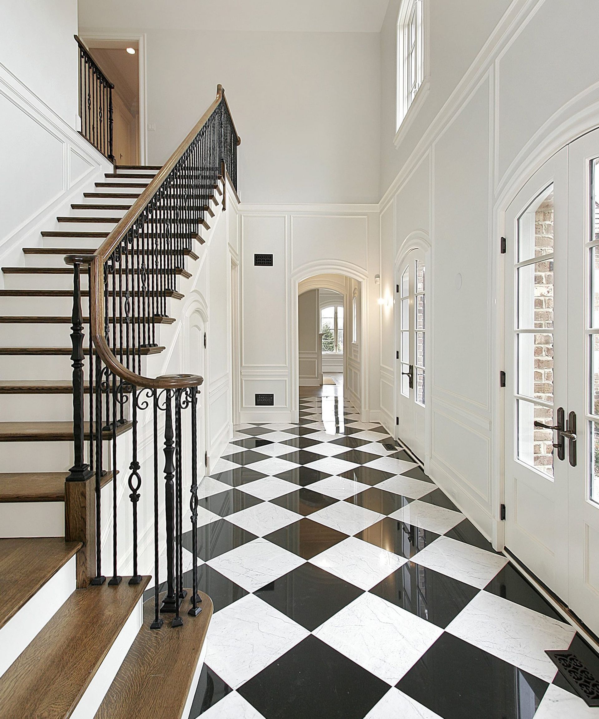 A hallway with a black and white checkered floor and stairs.