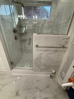 Modern white-tile bathroom with a bathtub and black fixtures, plus a blue accent band and wall-mounted shower.