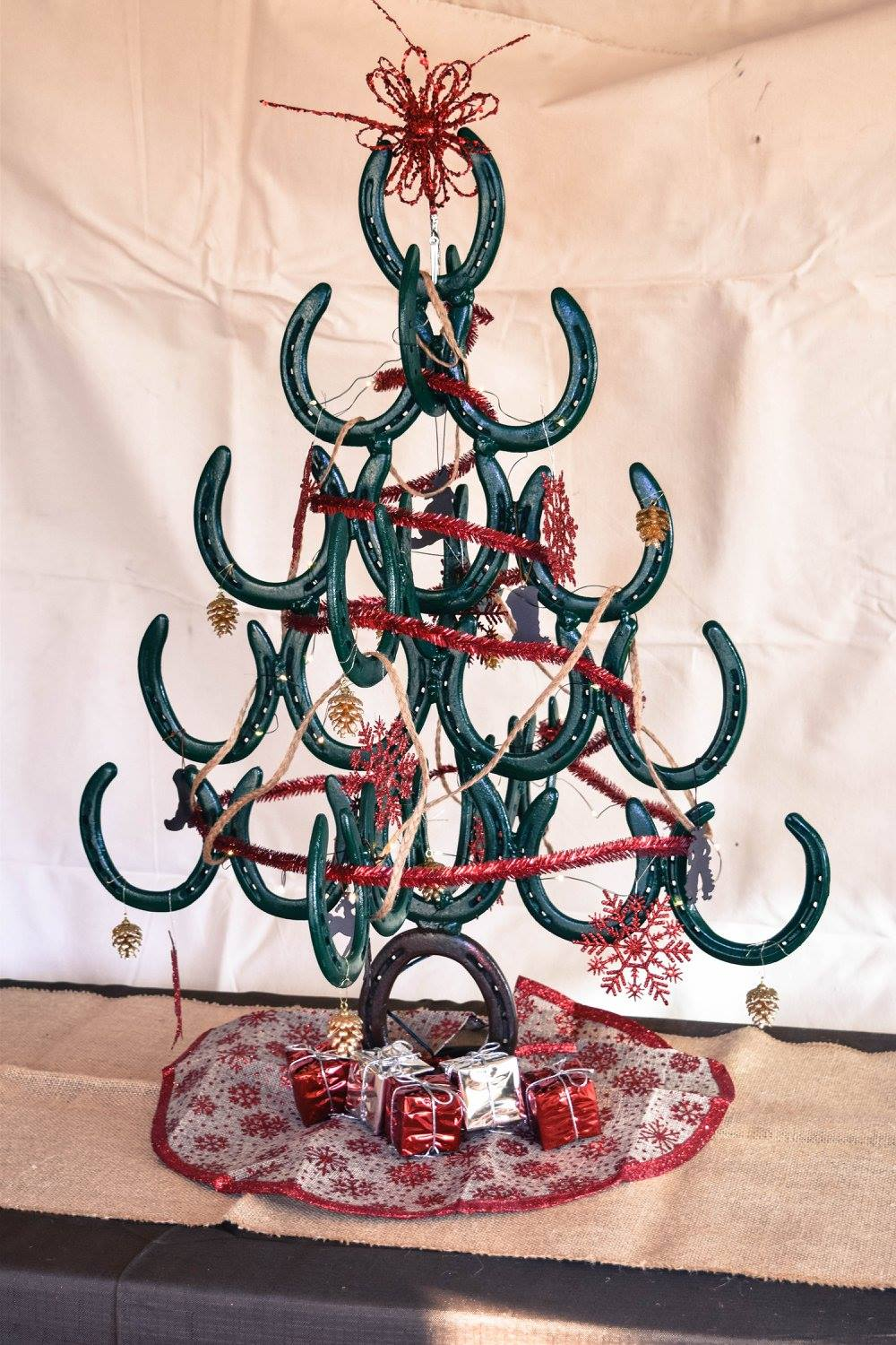 Teal pipe-cleaner Christmas tree with red garland and gifts on a white backdrop