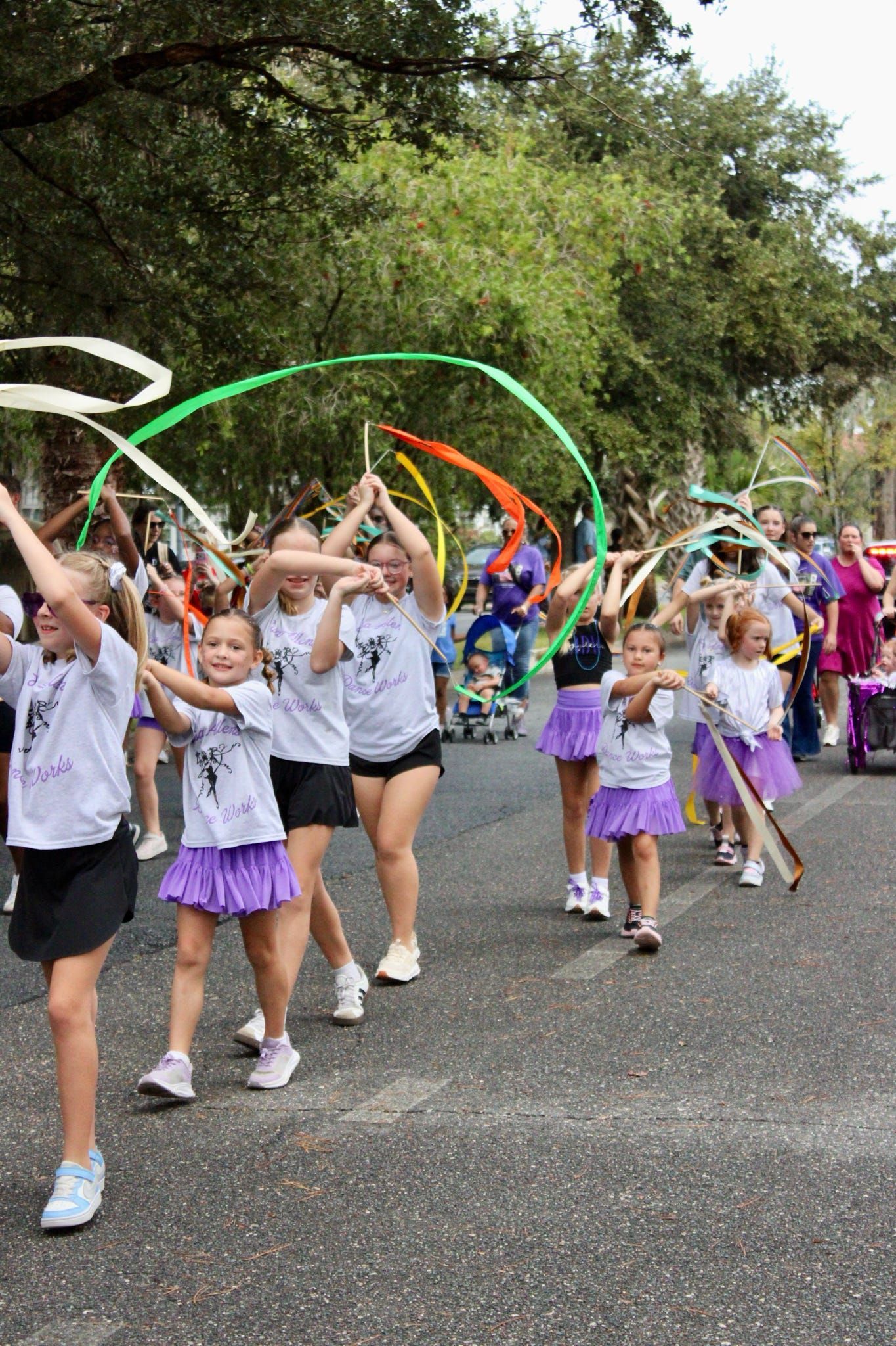 Children marching outdoors with colorful ribbons in a parade