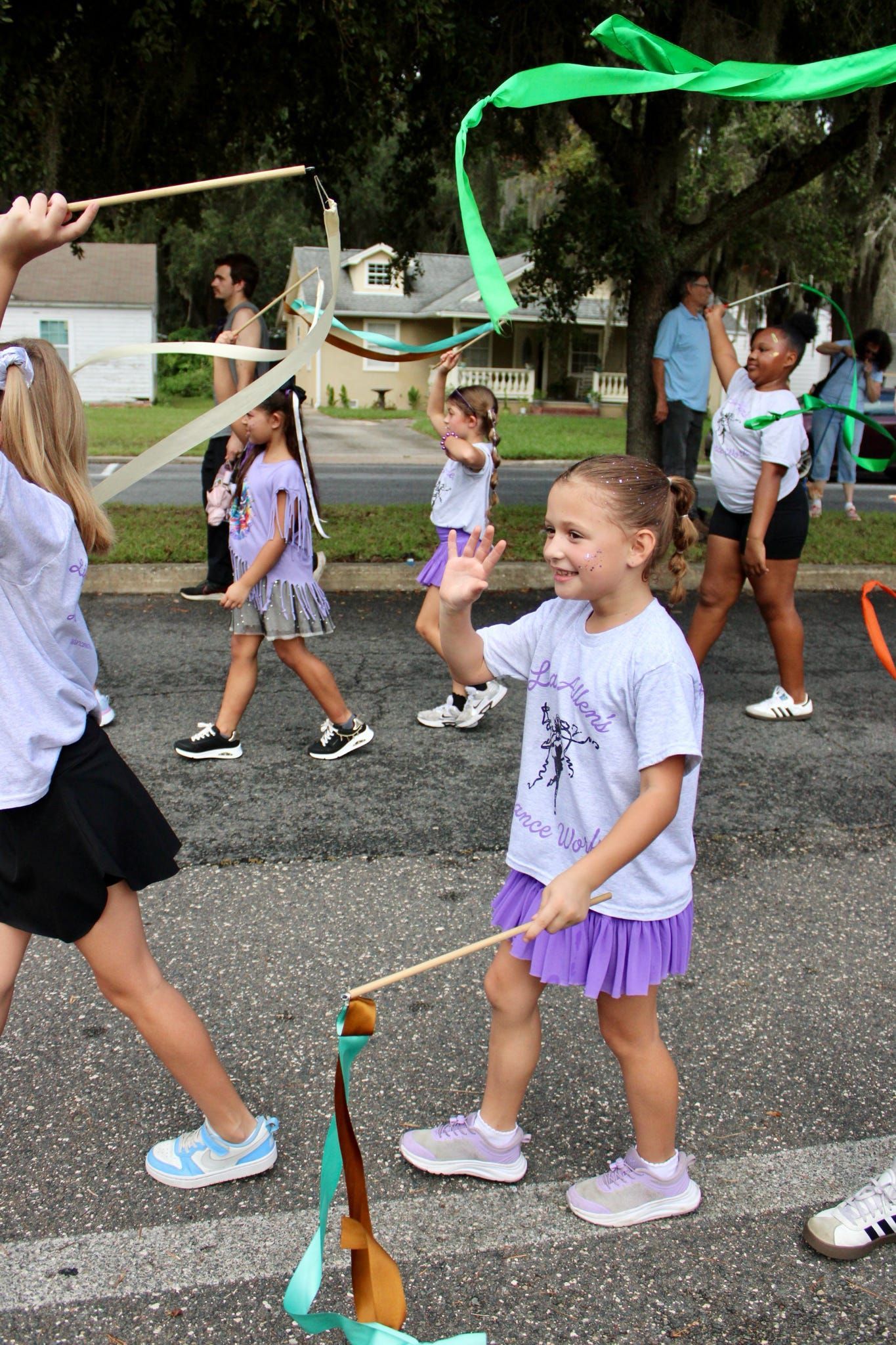 Children playing with streamers outdoors on a paved path during a race event