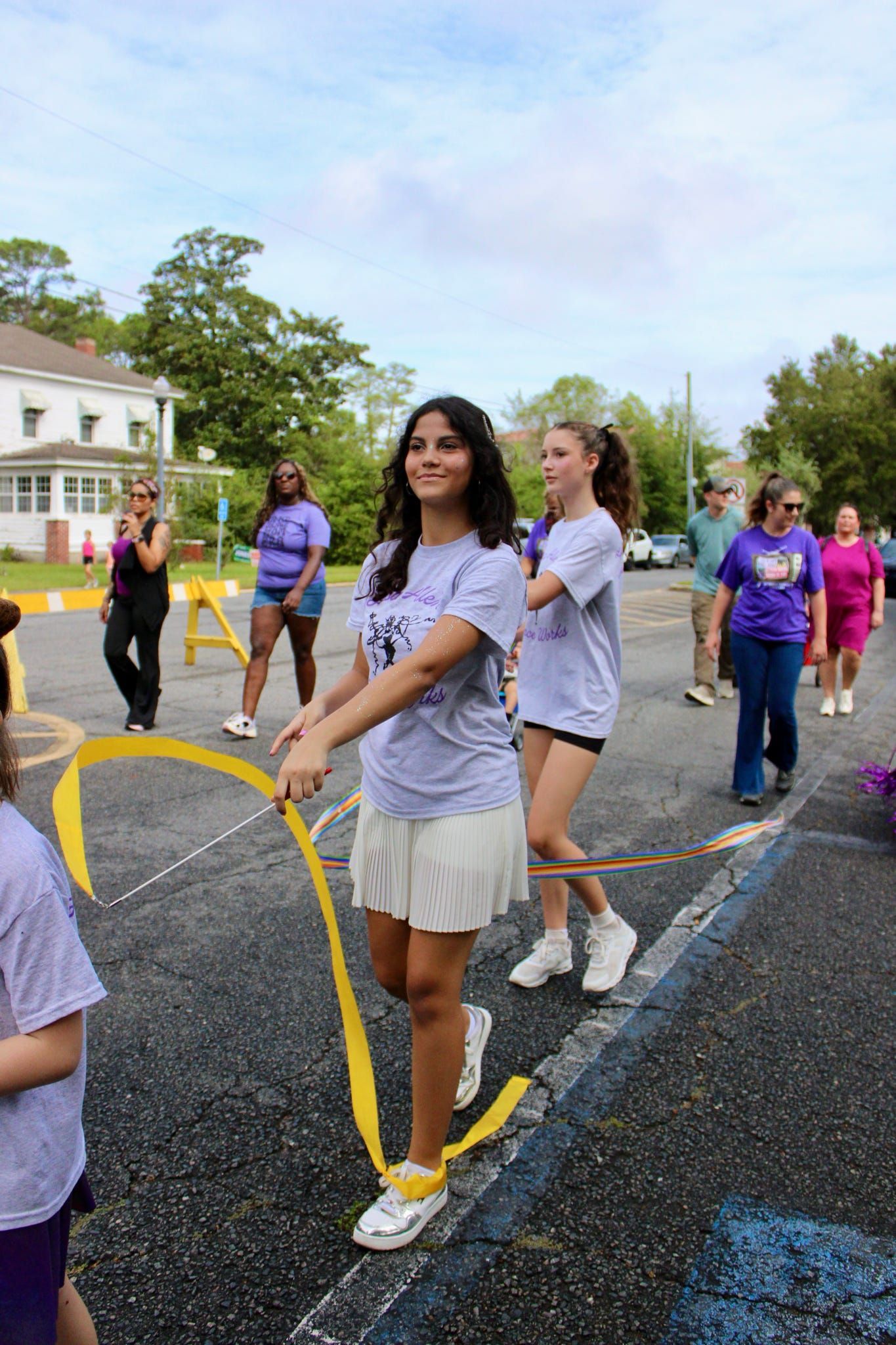 People standing outdoors on a road, holding yellow ropes during a group activity.