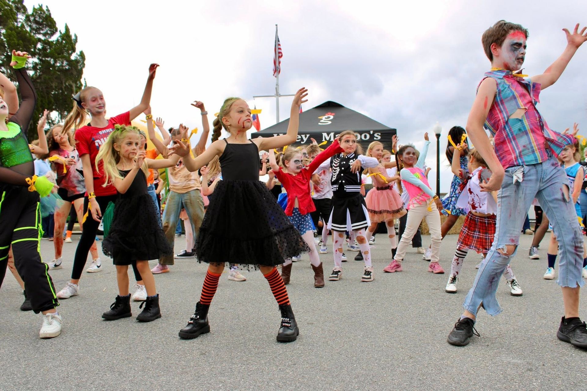 Children dancing in colorful costumes outdoors at a lively street event