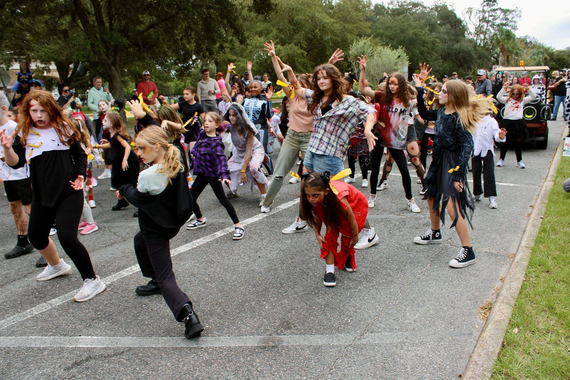 Children dancing in a park path, many with arms raised and moving together