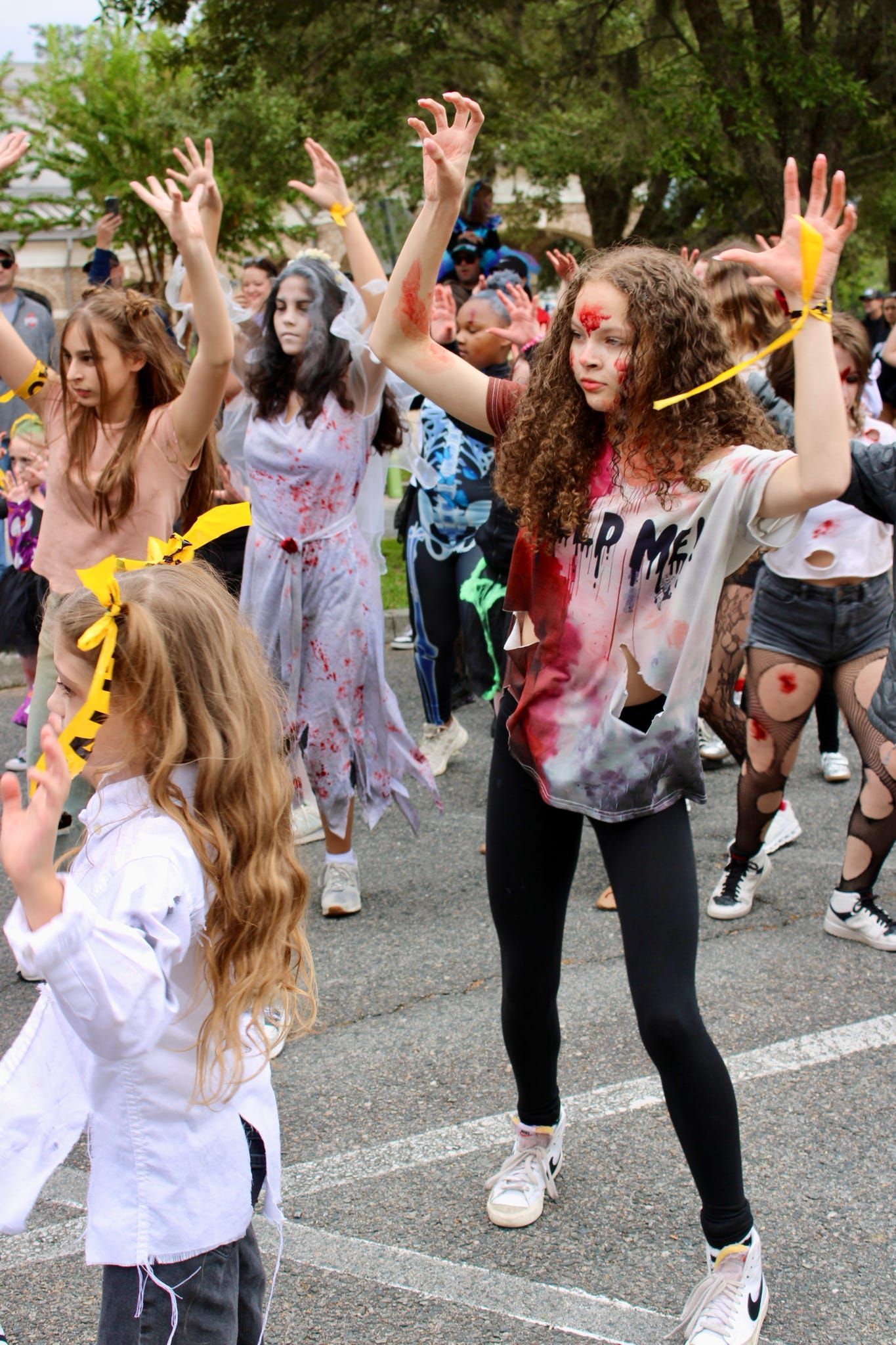 People dancing in a street parade, with colorful paint and streamers.