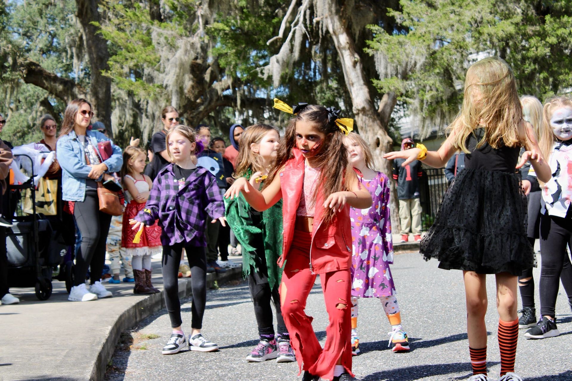 Children dancing outdoors in colorful costumes during a street performance