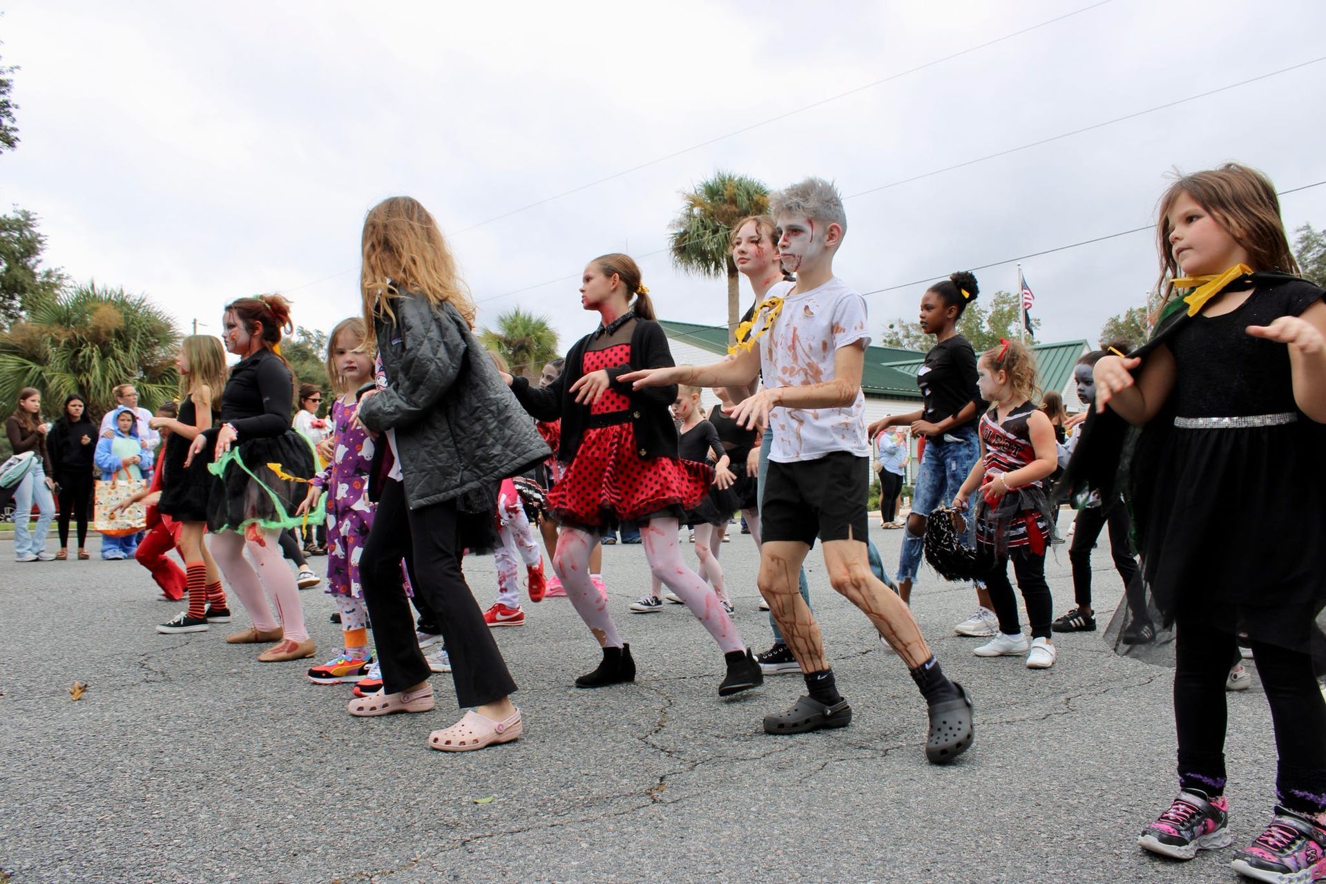 Group of people dancing outdoors on a street, wearing black and red costumes in a coordinated performance