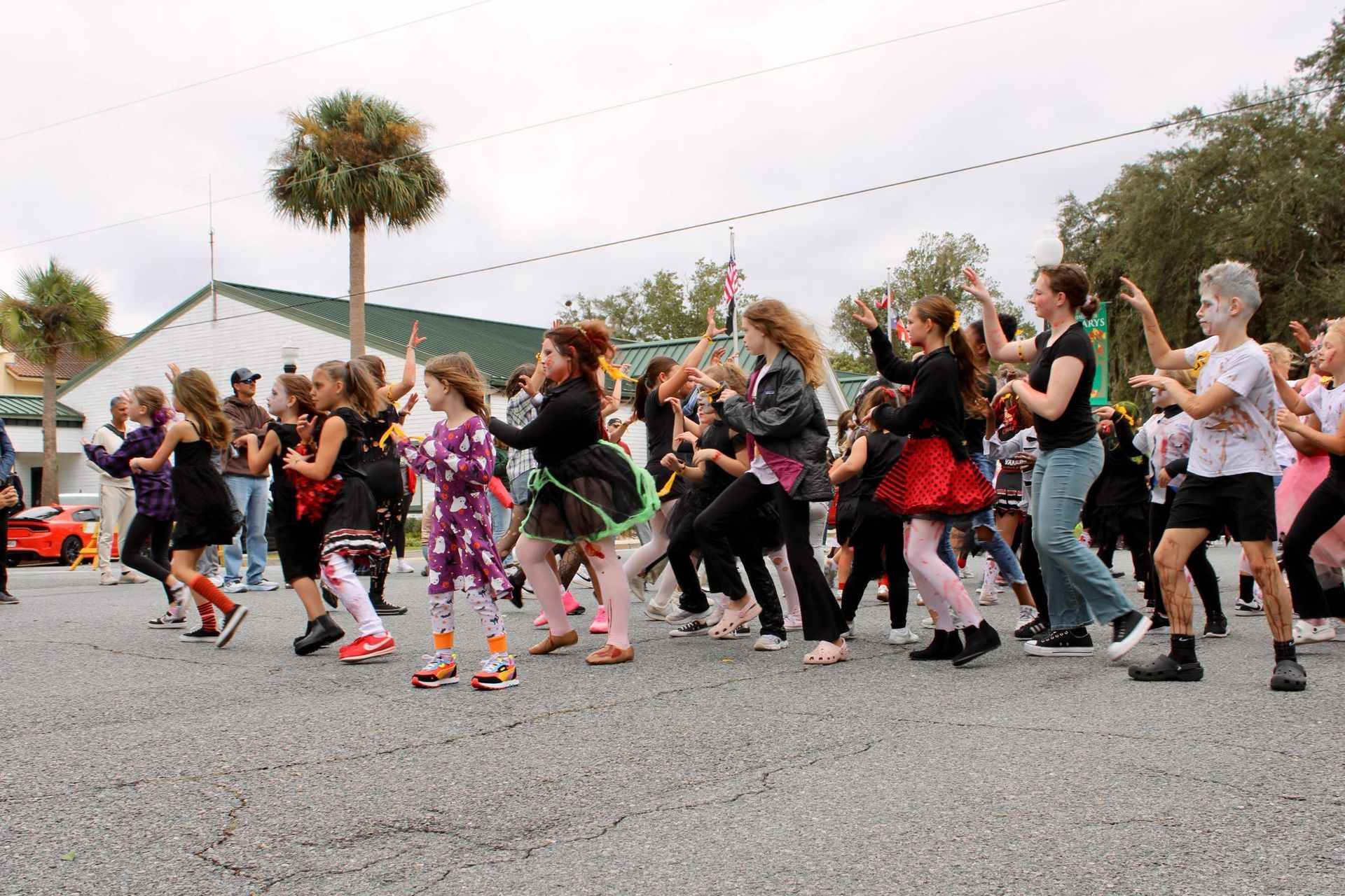 Children dancing in a street parade, wearing colorful costumes and moving in unison.