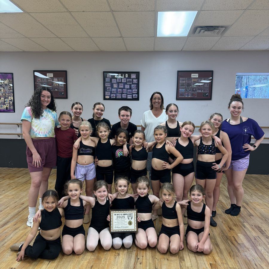 Dance team group posing in studio with trophies and certificate, wearing black and purple uniforms