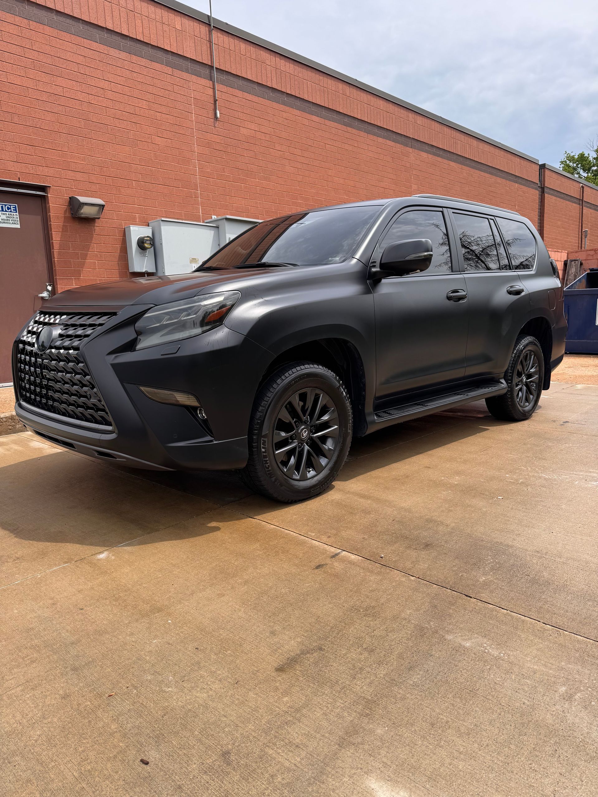 Black SUV parked beside a brick building on a wet driveway