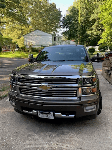 Front view of a gray pickup truck parked on a tree-lined residential street