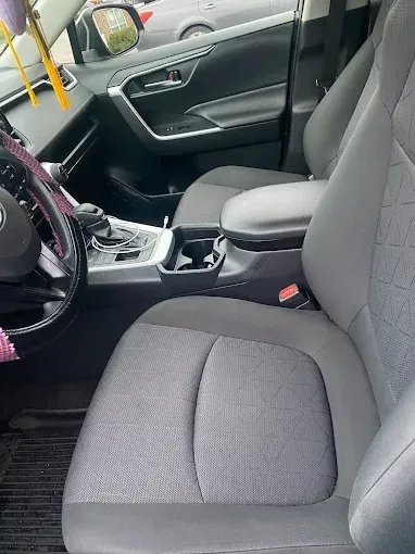 Front passenger seat and center console of a gray car interior, with door panel and steering wheel visible.
