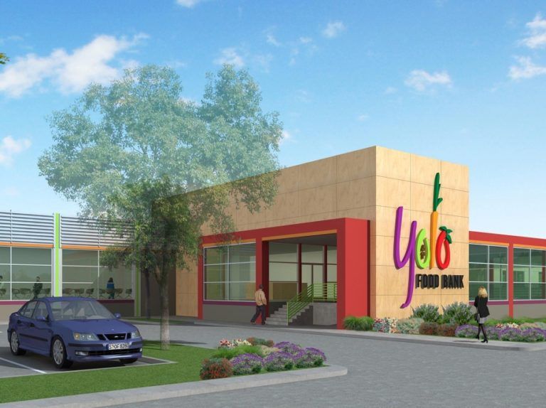 Exterior of Yoo Food Bank, beige building with red trim and a large logo. Car parked in front.