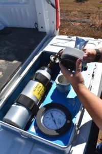 Person handling equipment in a truck bed. Includes a pressurized cylinder, gauge, and a filter.
