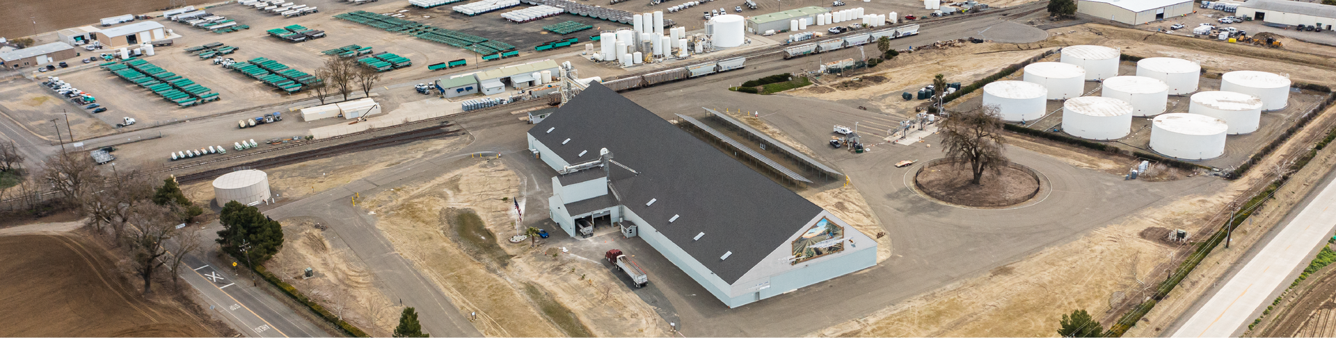 Aerial view of industrial site with building, storage tanks, and equipment.