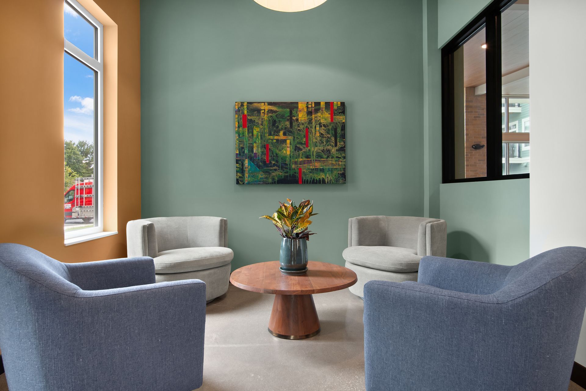 Modern living room with black double doors, large windows, and a wicker chair by colorful wall art