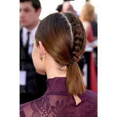 A woman wearing a purple dress and a braided ponytail.