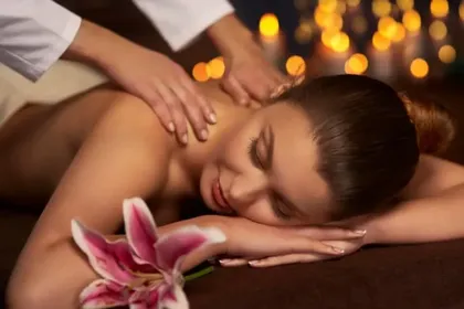 A woman is getting a massage at a spa with a flower in the foreground.
