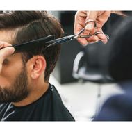 A man is getting his hair cut by a barber with scissors.